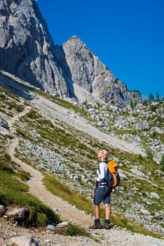 Young woman on a sunny day hiking in high mountains