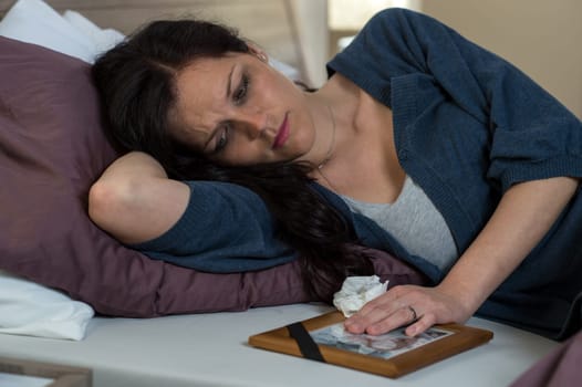 Mourning woman looking at her dead husband's photo