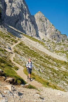 Young woman on a sunny day hiking in high mountains