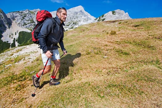 Young man on a sunny day hiking in high mountains