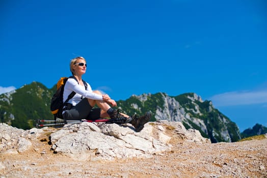 Young woman on a sunny day hiking in high mountains