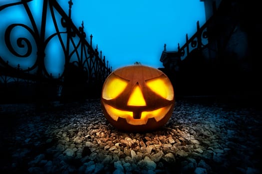 A glowing Jack O Lantern in a dark mist graveyard on Halloween