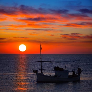 Ibiza sunset  view and menorquina fisherboat from Formentera orange sky