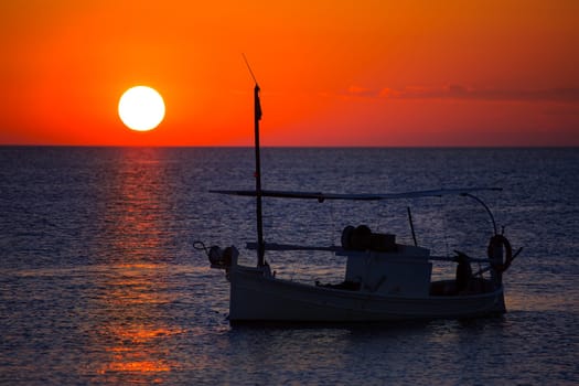 Ibiza sunset  view and menorquina fisherboat from Formentera orange sky