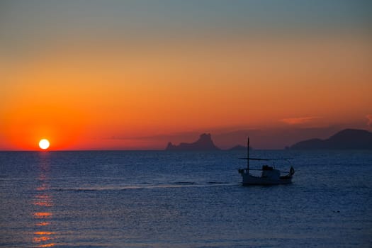 Ibiza sunset Es Vedra view and menorquina fisherboat from Formentera orange sky