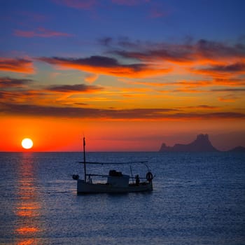 Ibiza sunset Es Vedra view and menorquina fisherboat from Formentera orange sky