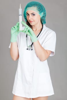 Young female doctor with syringe.  Doctor with syringe on grey background