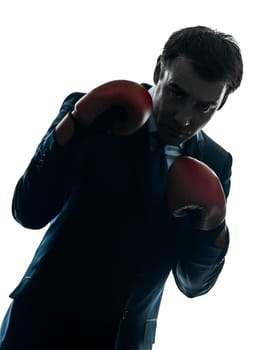 one caucasian businessman with boxing gloves   in silhouette studio isolated on white background