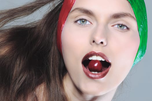 beauty portrait of a young caucasian woman biting eating cherry