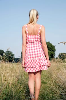Young attractive woman walks across a meadow