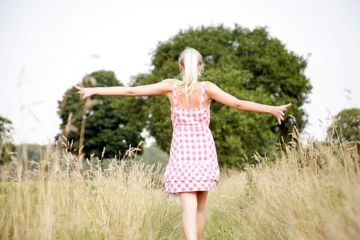 Young attractive woman walks across a meadow