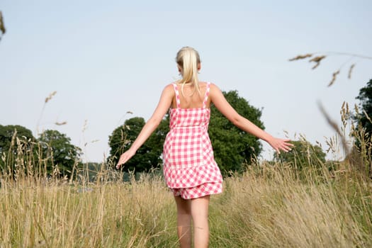 Young attractive woman walks across a meadow