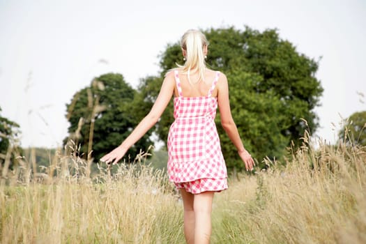 Young attractive woman walks across a meadow
