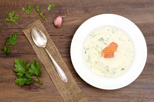 Frothy herb soup with salmon in a white plate