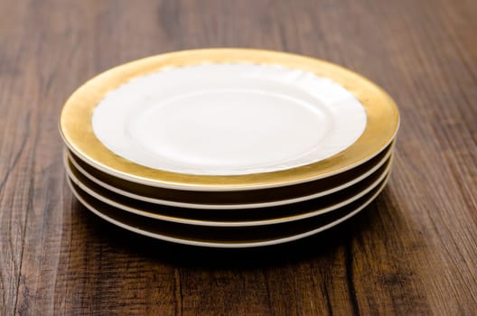 Four small plates with golden rims on a pile