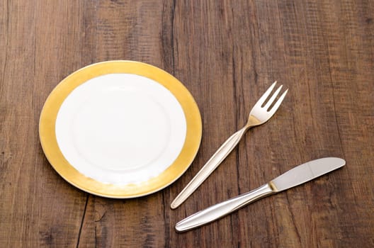 Place setting consisting of plate,knife and fork on a dining table