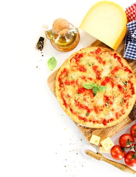 Top view of a pizza Margherita surrounded by ingredients like tomato, cheese, basil, olive oil and pepper and kitchen tools