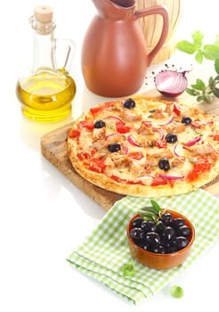Pizza made of tuna, olives, onion and basil over a wooden board surrounded by the ingredients