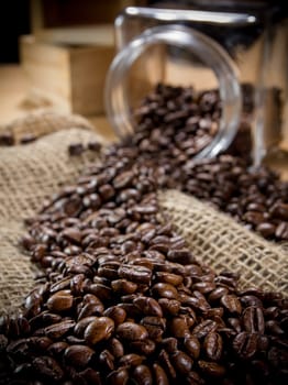 Black roasted coffee beans in a small burlap sack