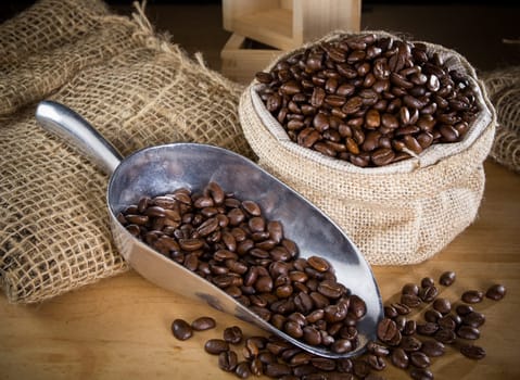 Black roasted coffee beans in a small burlap sack