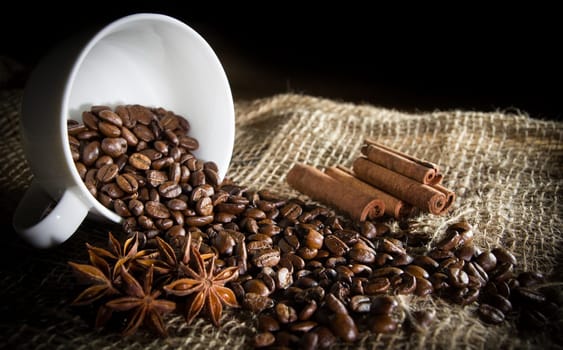 Black roasted coffee beans in a small burlap sack