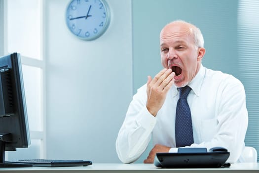 A business man  at his desk yawning