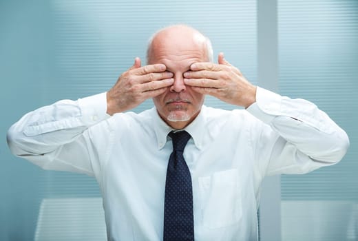 businessman covering his eyes with his hands