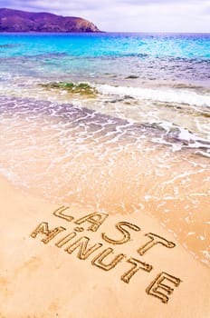 Last Minute written on sand, being washed away by waves, vacation concept