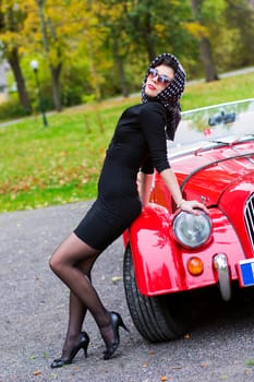 Woman in black posing on red car front