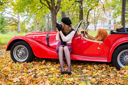 Woman take picture with red car on background