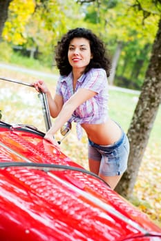 Woman in shirt posing on red car side