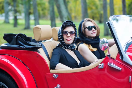 Fashionable women at retro car with dark glasses