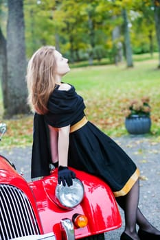 Woman in black posing on retro car headlight