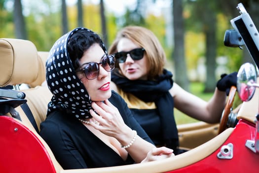 Pretty women with dark glasses adjust spotted scarf