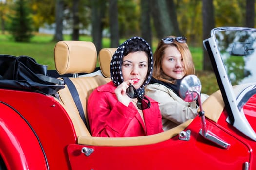 women at retro car look interested and satisfied