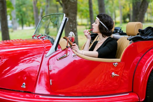 Pretty woman stains the lips before car mirror