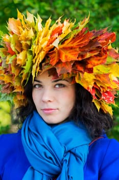 Woman with maple leaves on head look straight