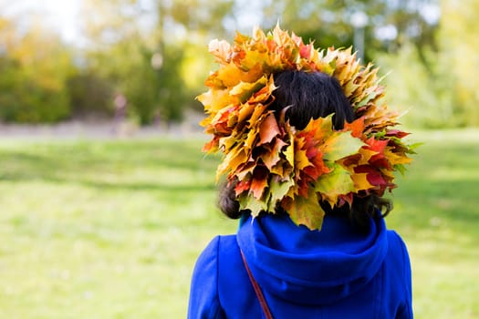 Woman with maple leaves on head from behind