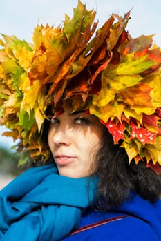 Woman with maple leaves on head look mysteriously