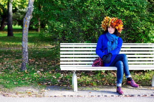 Woman with leaves on head on park bench