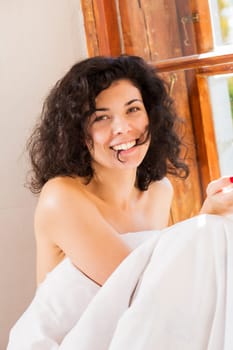 Smiling pretty woman under blanket bite hair perm