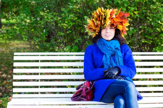 Satisfied young woman with maple leaves on head