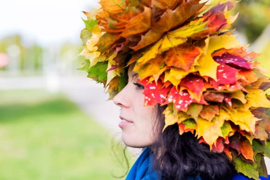 Woman with maple leaves on head from side