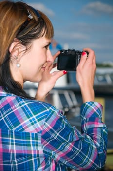 Exterior shot of young brunette woman wearing sunglasses and camera in side view over shoulder