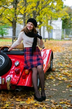 Young woman in skirt posing on car back