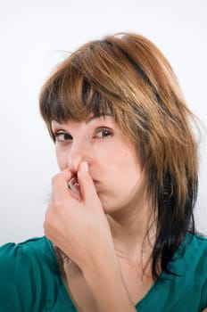 Head-and-shoulder shot of a young woman looking into the camera holding her nose