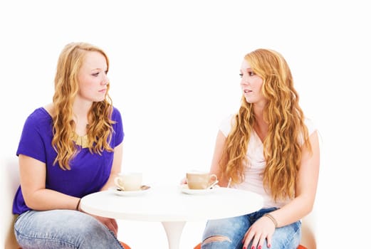 Serious young women talking over coffee in front of a white background