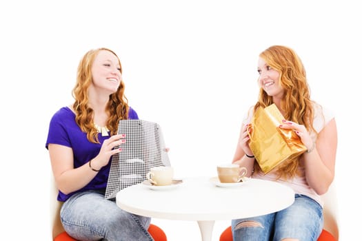 Two happy women having coffee with shopping bags against a white background