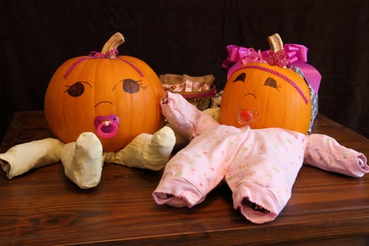 Two pumpkins dressed up as princess babies with pacifiers.