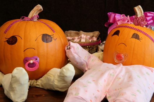 Two pumpkins dressed up as princess babies with pacifiers.